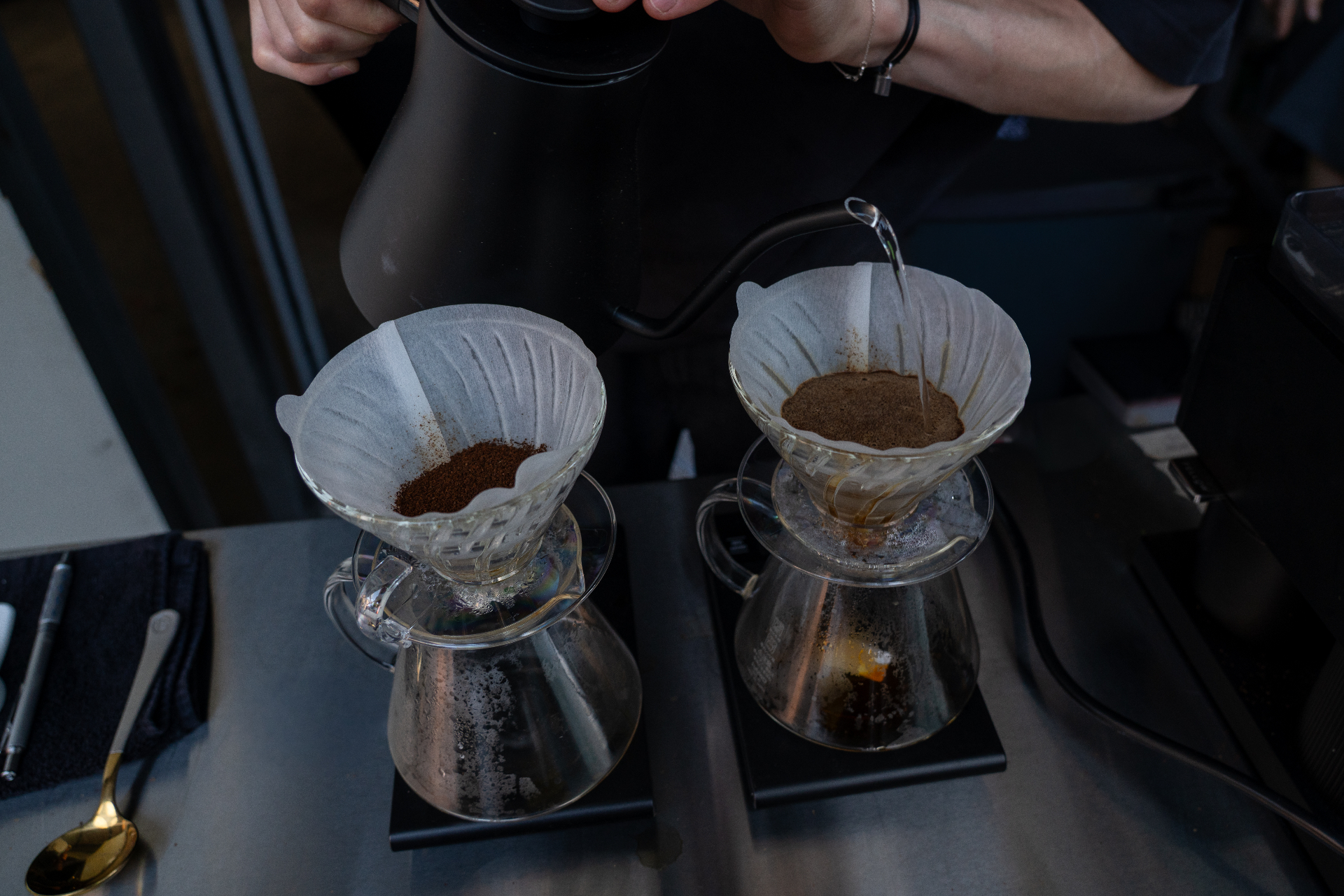 Barista pouring water over two glass pour-over coffee drippers